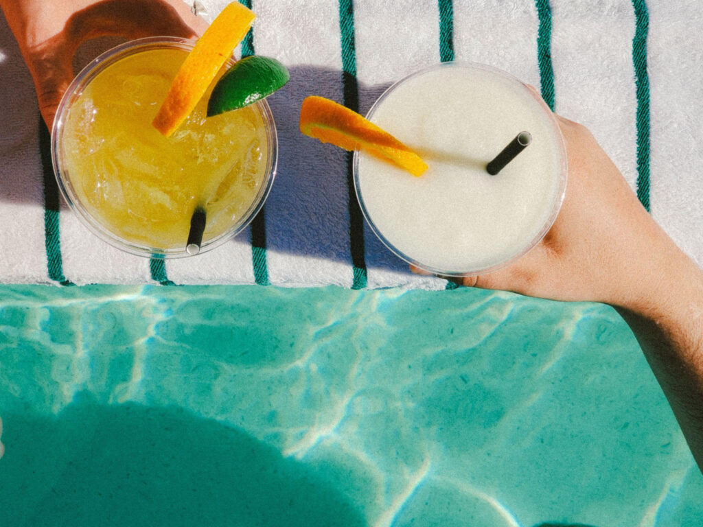 Close of up of hands holding frozen drinks on beach towel
